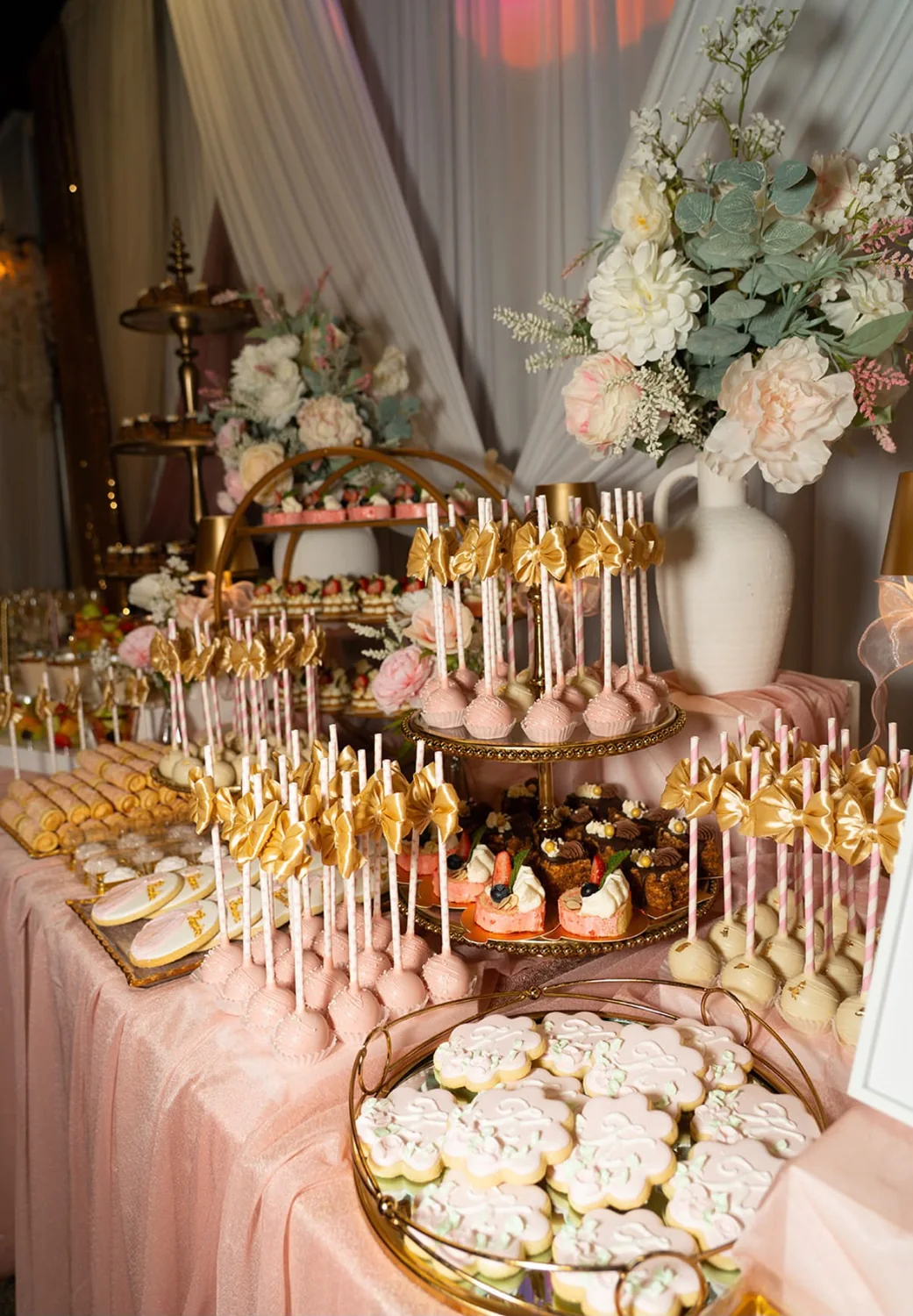 Mesa de postres con decoración floral y detalles dorados