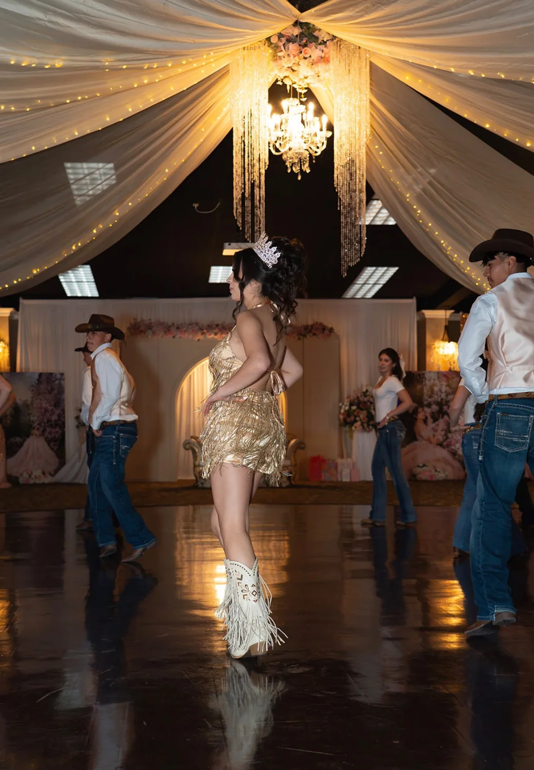 Quinceañera durante baile sorpresa con acompañantes bajo decoración iluminada