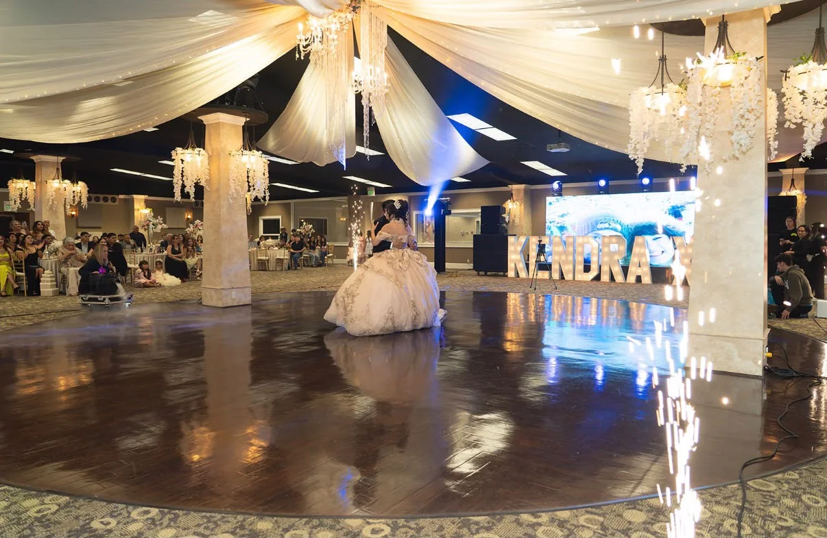 Quinceañera bailando en pista con luces y decoración de salón